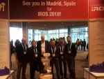 PAL Robotics' team posing under the banner for IROS 2018 in Madrid