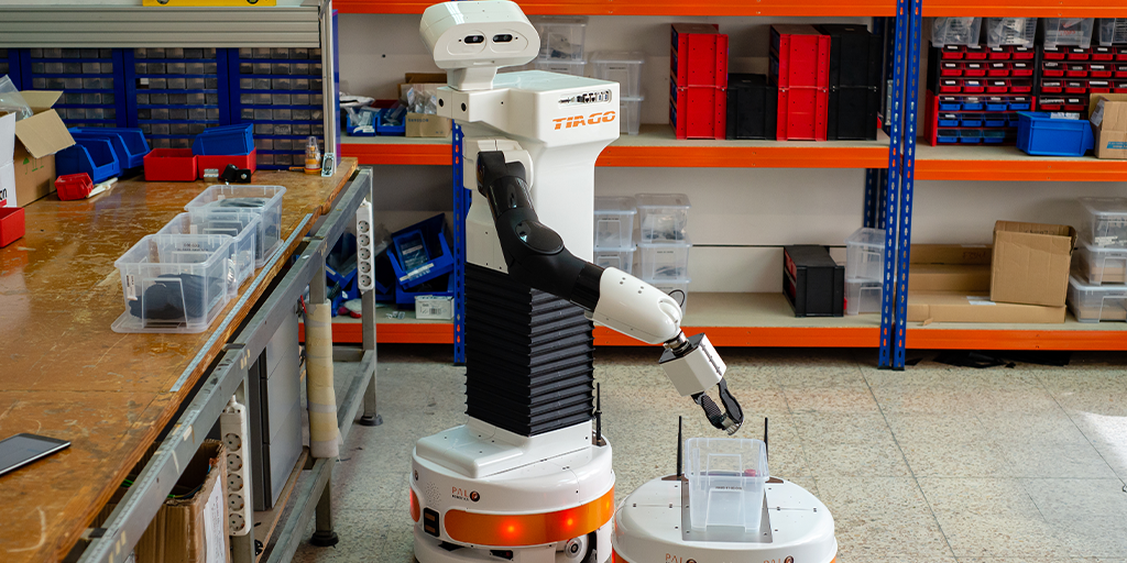 The mobile manipulator robot TIAGo and the autonomous mobile robot (AMR) TIAGo Base working in a warehouse together with humans within project Co4Robots
