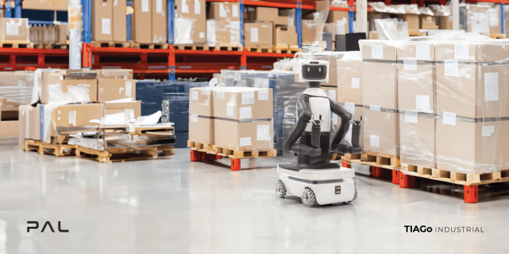 The TIAGo Pro mobile manipulator by PAL Robotics, with a humanoid torso and a gripper arm, navigates a warehouse floor filled with pallets of packaged goods, embodying advanced industrial robotics technology, to describe the main idea of the TIAGo Industria project. Industrial robotics